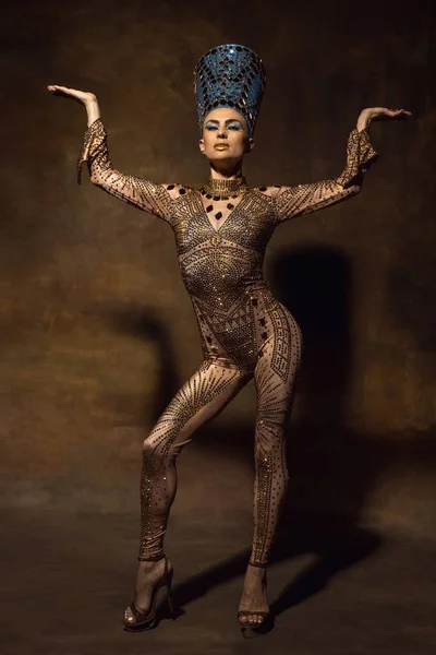 Młoda kobieta w obrazie Nefertiti w sztuce performance izolowane na brązowym tle vintage. Styl retro, porównanie koncepcji ery. — Zdjęcie stockowe