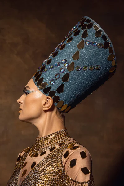 Close-up bela jovem na imagem de Nefertiti em performance de arte isolada em fundo vintage marrom. Estilo retro, comparação do conceito eras. Vista lateral — Fotografia de Stock