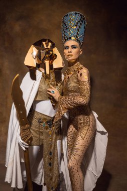 Nefertiti 'nin sanat performansındaki görüntüsü gibi genç bir kadın. Kahverengi renkli arka planda izole edilmiş. Retro biçimi, dönemin karşılaştırması.