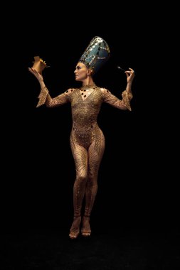 Nefertiti 'nin sanat performansını yansıtan genç ve güzel bir kadın karanlık arka planda modern fast food tadıyor. Retro tarzı, çağların karşılaştırılması, mizah anlayışı.