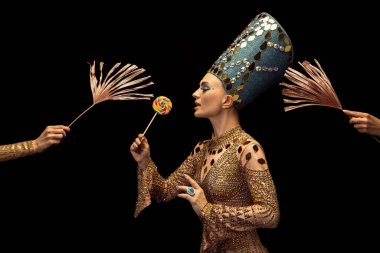 Nefertiti 'nin sanat performansını yansıtan genç ve güzel bir kadın koyu arkaplanda izole tablet kullanıyor. Retro tarzı, çağların karşılaştırılması, mizah anlayışı.