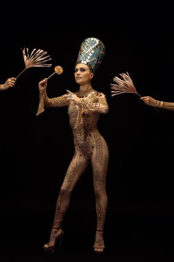 Nefertiti 'nin sanat performansını yansıtan genç ve güzel bir kadın koyu arkaplanda izole tablet kullanıyor. Retro tarzı, çağların karşılaştırılması, mizah anlayışı.