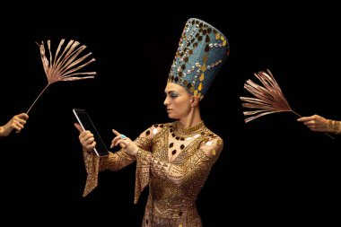 Esmer arka planda izole edilmiş tablet kullanan Nefertiti 'nin sanat performansını gösteren genç bir kadın. Retro tarzı, çağların karşılaştırılması, mizah anlayışı.