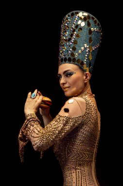 Nefertiti 'nin karanlık arka planda izole edilmiş sanat performansındaki genç kadın portresi. Retro tarzı, çağların karşılaştırılması, mizah anlayışı.