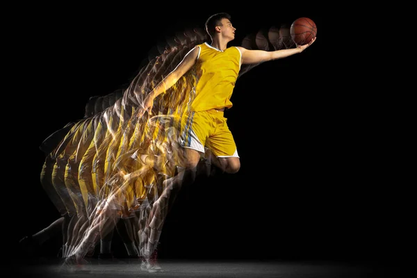 Voo. Jovem jogador de basquete caucasiano em movimento e ação isolado em fundo escuro com efeito estroboscópio. Conceito de esporte profissional, hobby. — Fotografia de Stock
