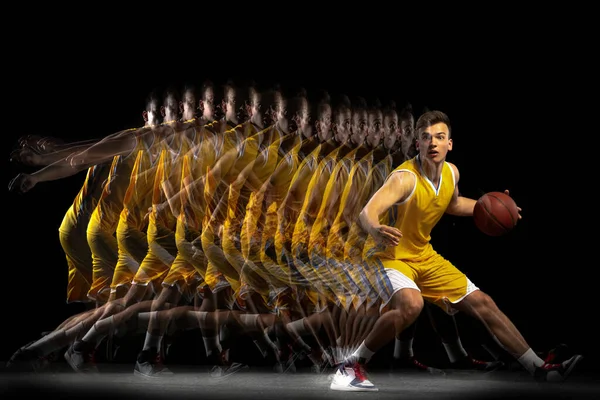 Jonge Kaukasische basketbalspeler in beweging en actie geïsoleerd op donkere achtergrond met stroboscoop effect. Concept van gezonde levensstijl, professionele sport, hobby. — Stockfoto