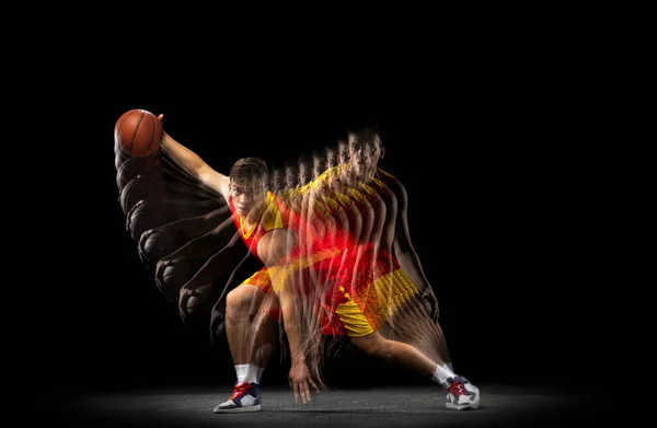 Een jonge basketbalspeler training met bal geïsoleerd op donkere achtergrond met stroboscoop effect. Begrip professionele sport, hobby. — Stockfoto