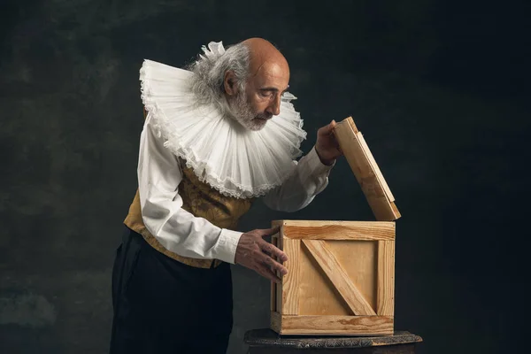 Uomo anziano dai capelli grigi, attore o mago isolato su sfondo vintage scuro. Stile retrò, confronto del concetto di epoche. — Foto Stock