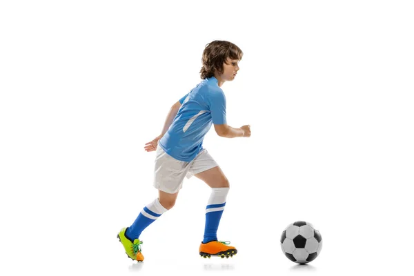 Un niño preescolar, futbolista en acción, entrenamiento en movimiento aislado en el fondo blanco del estudio. Concepto de deporte, juego, hobby — Foto de Stock