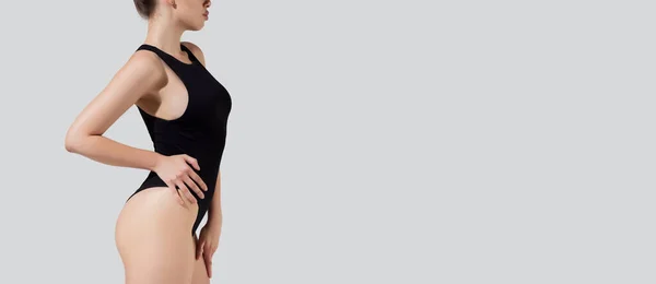 Ulotka z młodą, piękną, szczupłą kobietą w czarnej bieliźnie, strój kąpielowy pozujący na szarym tle studia. Kopiuj miejsce na reklamę — Zdjęcie stockowe