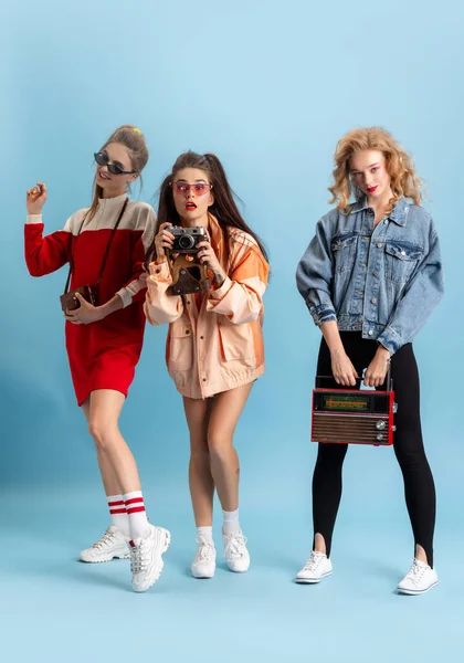 Hezké mladé ženy v retro 90. letech módní styl, oblečení pózuje izolované přes modré pozadí studia. Pojem éry srovnání, krásy, módy a mládeže. — Stock fotografie