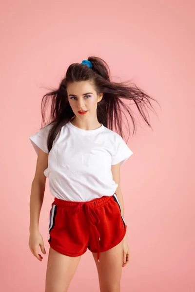 Portrait of adorable pretty young girl in retro 90s fashion style, outfits posing isolated over pink studio background. Concept of eras comparison, beauty, fashion and youth. — Stock Photo, Image