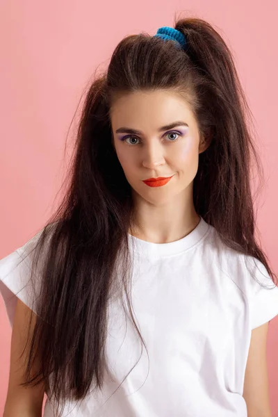 Close-up adorable pretty young girl with bright makeup and hairdo in retro 90s fashion style isolated over pink studio background. Concept of eras comparison, beauty, fashion and youth. — Stock Photo, Image