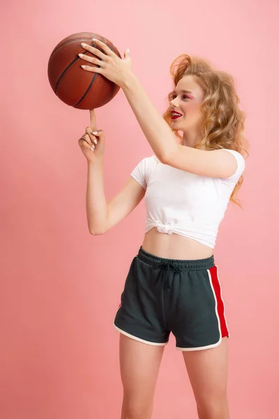 Portret młodej dziewczyny, tenisistka w stylu retro lat 90., stroje bawiące się piłką na różowym tle studia. Koncepcja porównywania epok, piękna, mody i młodzieży. — Zdjęcie stockowe