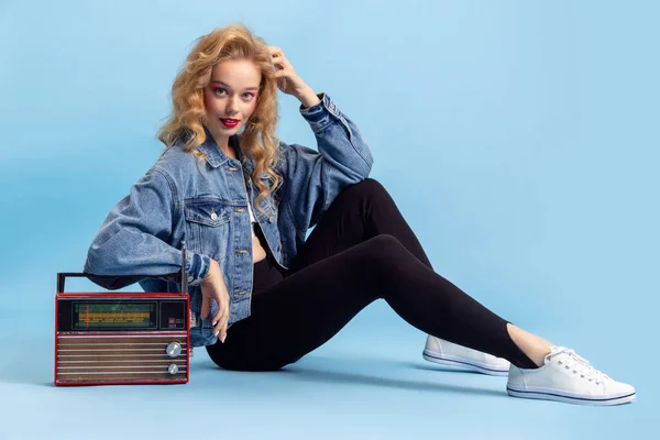 Retrato de menina atraente em retro estilo de moda dos anos 90, roupas posando isolado sobre fundo estúdio azul. Conceito de comparação eras, beleza, moda e juventude. — Fotografia de Stock