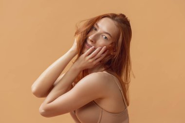 İç çamaşırlı, kumlu stüdyo arkasında yalnız poz veren güzel, kızıl saçlı bir kadın. Fitness, diyet, spor, doğal güzellik ve estetik kozmetik konsepti.