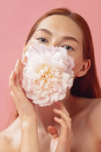 Retrato de close-up da bela mulher ruiva com flor isolada sobre o chão de fundo estúdio rosa. Cor nua, dieta, cosméticos, beleza natural e conceito de cosmetologia estética. — Fotografia de Stock