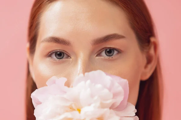 Retrato de close-up da bela mulher ruiva com flor isolada sobre o chão de fundo estúdio rosa. Cor nua, dieta, cosméticos, beleza natural e conceito de cosmetologia estética. — Fotografia de Stock