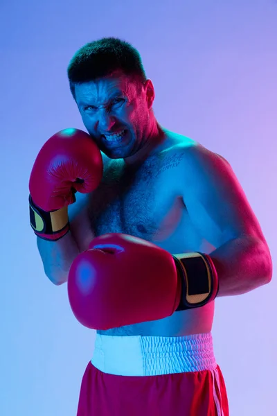 Retrato de hombre caucásico, boxeador profesional en ropa deportiva aislado en el fondo del estudio en luz de neón gradiente. Concepto de deporte, actividad, movimiento, bienestar. — Foto de Stock