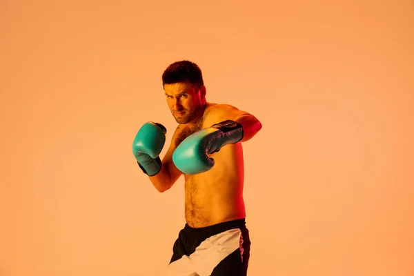 One professional male boxer in sportswear and gloves isolated on yellow studio background in neon light. Concept of sport, activity, movement, wellbeing. — Stock Photo, Image