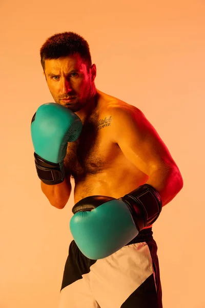 Közelkép profi férfi bokszoló sportruházatban és kesztyűben, sárga stúdió háttérrel elszigetelve neon fényben. A sport, a tevékenység, a mozgás és a jólét fogalma. — Stock Fotó