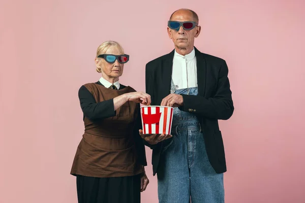 Homme et femme âgés sérieux dans des tenues paysannes vintage rétro isolées sur fond de studio rose. Style rétro, comparaison des époques et concept culturel. — Photo