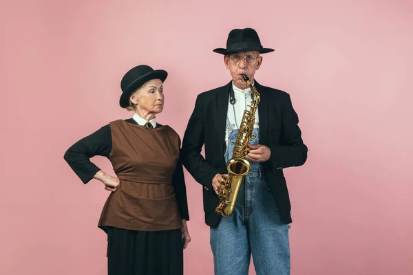 Homem e mulher idosos graves em trajes de agricultor vintage retro isolados em fundo de estúdio rosa. Estilo retrô, comparação de eras e conceito cultural. — Fotografia de Stock