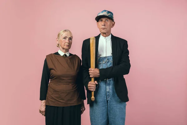 Homem e mulher idosos graves em trajes de agricultor vintage retro isolados em fundo de estúdio rosa. Estilo retrô, comparação de eras e conceito cultural. — Fotografia de Stock