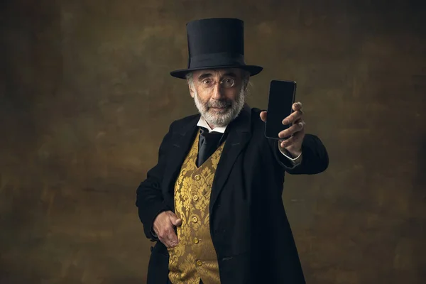 Homem sênior bonito, cavalheiro, aristocrata ou ator falando no telefone isolado em fundo vintage escuro. Estilo retro, comparação do conceito eras. — Fotografia de Stock