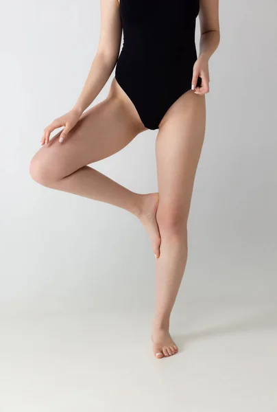 Štíhlé ženské nohy, tělo v černém spodním prádle izolované přes šedé pozadí studia. Koncept přírodní krásy. — Stock fotografie