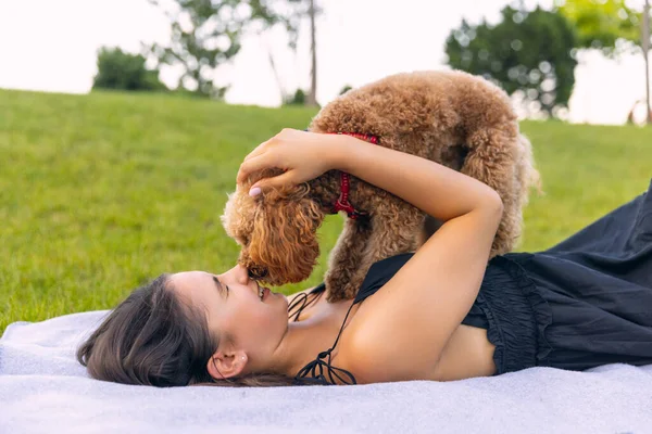 Hermosa chica caucásica y su mascota, perrito caniche dorado paseando en el parque público, al aire libre. Hora de verano. Emociones sinceras. concepto de actividades de ocio — Foto de Stock