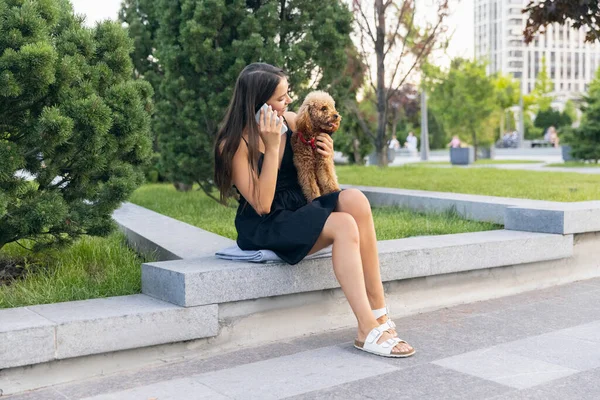 Pretty girl and her pet, little golden poodle dog strolling in public park, outdoors. Summer time. Sincere emotions. leisure activities concept — Stock Photo, Image