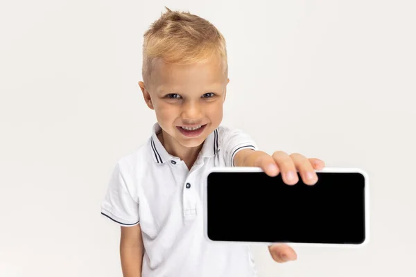 Close-up portrait of Caucasian preschool boy with phone isolated on white studio background. Copyspace for ad. Childhood, education, emotion concept — Stockfoto