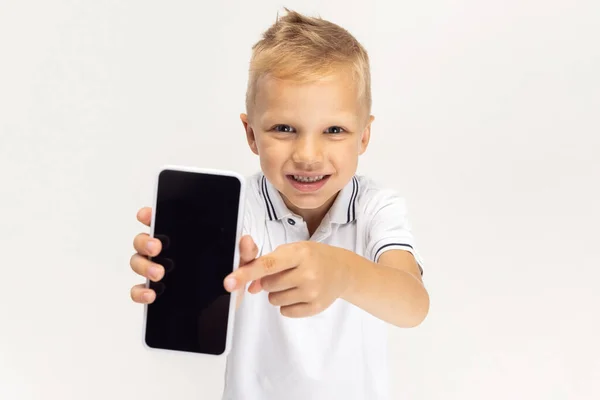 Close-up portrait of Caucasian preschool boy with phone isolated on white studio background. Copyspace for ad. Childhood, education, emotion concept — Stockfoto