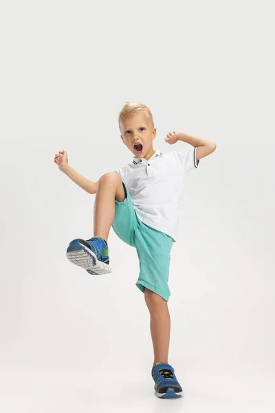 Portrait of cute preschool boy in shirt and shorts isolated on white studio background. Copyspace for ad. Childhood, education, emotion concept — Stockfoto