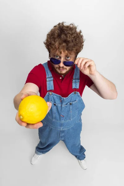 Hoge hoek uitzicht op grappige jongeman, boer met grote citroenen geïsoleerd over grijze studio achtergrond. Begrip beroepsactiviteit, werk. — Stockfoto