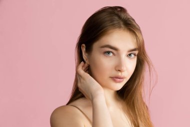 Pembe stüdyo arka planında izole edilmiş güzel, tapılası genç bir kız. Doğal güzellik, kaplıca, kozmetik ve estetik kozmetik konsepti.