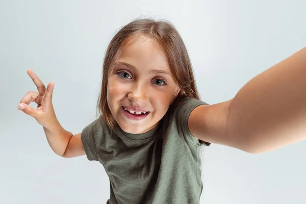 Close-up portrait of beautiful preschool smiling girl looking at camera isolated on white studio background. Copyspace for ad. Childhood, education, emotion concept — 图库照片