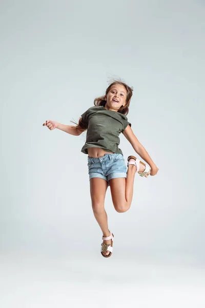 Повнометражний портрет красивої дошкільної усміхненої дівчини, що стрибає, грає ізольовано на сірому студійному фоні. Копія для реклами. Дитинство, освіта, концепція емоцій — стокове фото