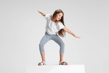 Beyaz stüdyo arka planında izole edilmiş büyük bir kutunun üzerinde duran beyaz anaokulu kızı. Kopyalama. Çocukluk, eğitim, duygu kavramı