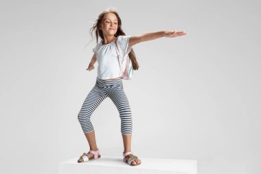 Beyaz stüdyo arka planında izole edilmiş büyük bir kutunun üzerinde duran beyaz anaokulu kızı. Kopyalama. Çocukluk, eğitim, duygu kavramı