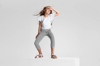 Beyaz stüdyo arka planında izole edilmiş büyük bir kutunun üzerinde duran beyaz anaokulu kızı. Kopyalama. Çocukluk, eğitim, duygu kavramı