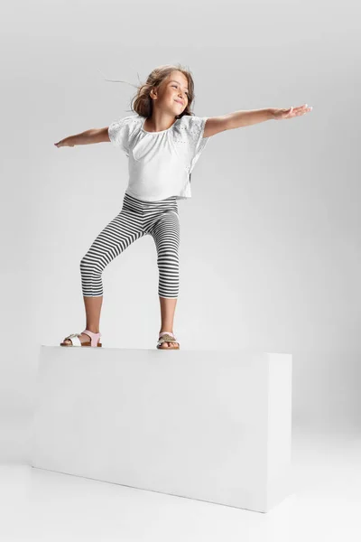 Beyaz stüdyo arka planında izole edilmiş büyük bir kutunun üzerinde duran beyaz anaokulu kızı. Kopyalama. Çocukluk, eğitim, duygu kavramı — Stok fotoğraf
