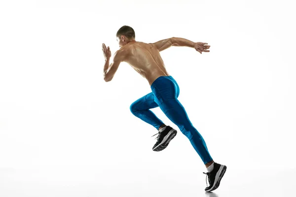 Un atleta masculino profesional caucásico, entrenamiento de corredor aislado en el fondo blanco del estudio. Hombre musculoso y deportivo. Concepto de deporte, estilo de vida saludable —  Fotos de Stock