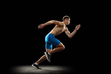 Beyaz tenli profesyonel bir erkek atlet, atlet eğitimi karanlık bir stüdyoda izole edilmiş. Kaslı, sportif bir adam. Spor anlayışı, sağlıklı yaşam tarzı