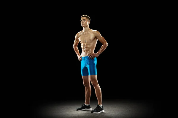Young sportsman, male athlete, runner standing isolated on dark studio background. Muscular, sportive man. Concept of sport, healthy lifestyle, wellness — Stock Photo, Image