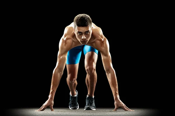 Zwycięzca. Portret młodego profesjonalnego sportowca, biegacza odizolowanego na ciemnym tle pracowni. Muskularny, wysportowany mężczyzna. Pojęcie sportu, zdrowy styl życia — Zdjęcie stockowe