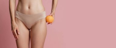 İnce, bronz tenli, iç çamaşırlı genç bir kadının pembe stüdyo arka planında izole edilmiş pozu. Doğal güzellik, anti-selülit tedavi konsepti. El ilanı