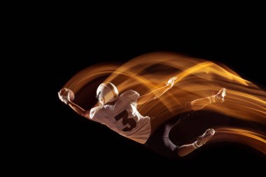 Genç bir adamın portresi, Amerikan futbolcu eğitimi karanlık stüdyo arka planında izole edilmiş, karışık neon ışıklı. Spor, rekabet ve güzellik kavramı