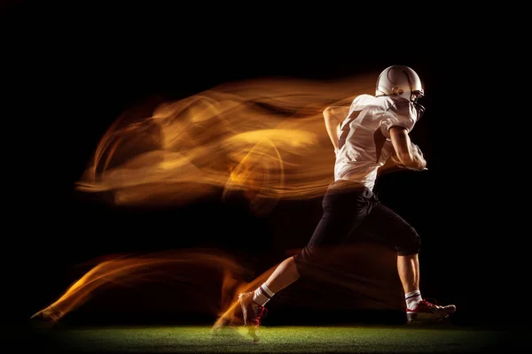 Портрет молодого чоловіка, тренування американського футболіста ізольовані на темній студії з змішаним неоновим світлом. Концепція спорту, конкуренції та краси — стокове фото